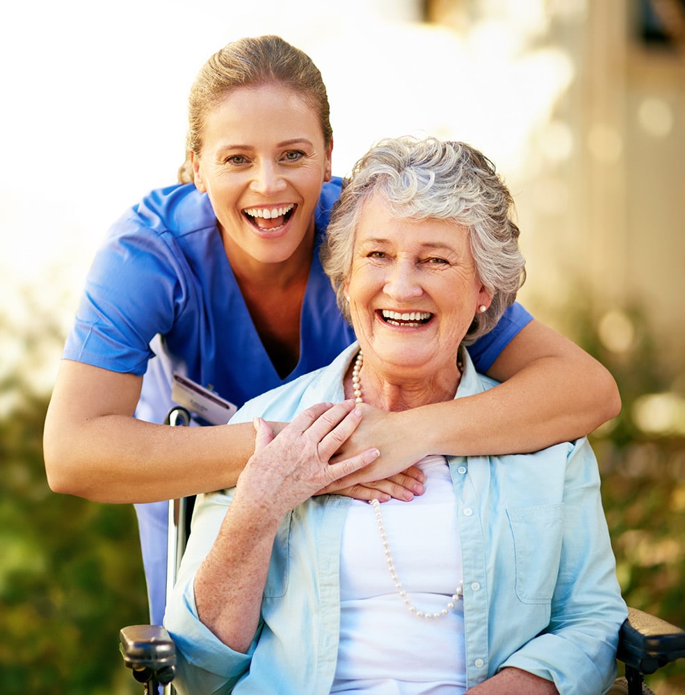 Woman in wheelchair and nurse smiling and embracing.