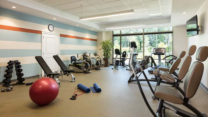 Fitness room at The Cardinal featuring free weights, ellipticals and other exercise equipment.