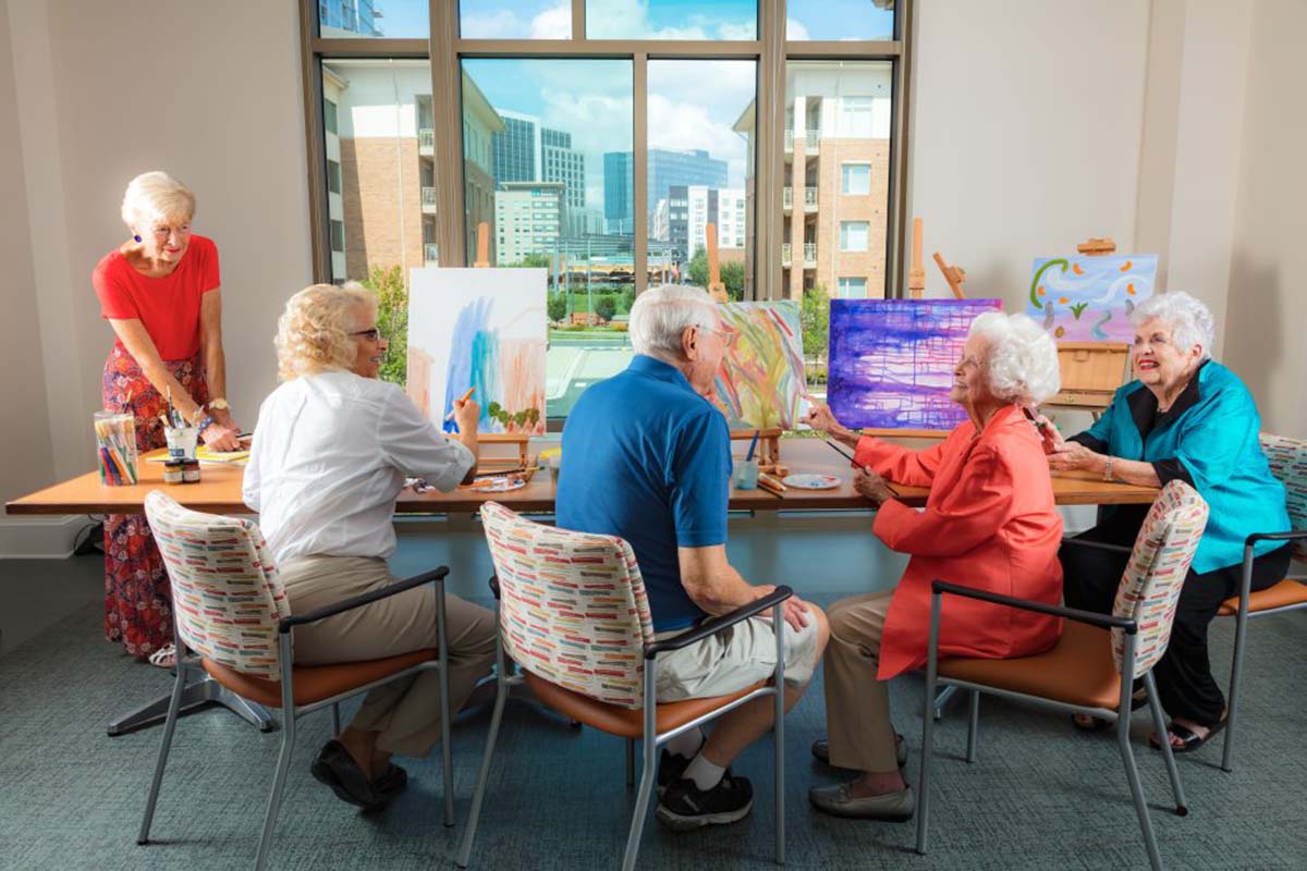 Group of Cardinal residents sitting down to paint during an art class at the community.